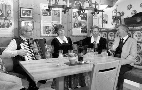 Rainer Quartett: Zillertaler Musiktradition Das Rainer Quartett mit Akkordeon an einem Tisch in einer holzgetäfelten Stube mit historischen Musikbildern.