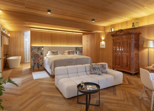 Suite Lavandula in MalisGarten Holzverkleidete Suite mit Doppelbett, hellem Sofa, historischem Schrank und freistehender Badewanne in MalisGarten.